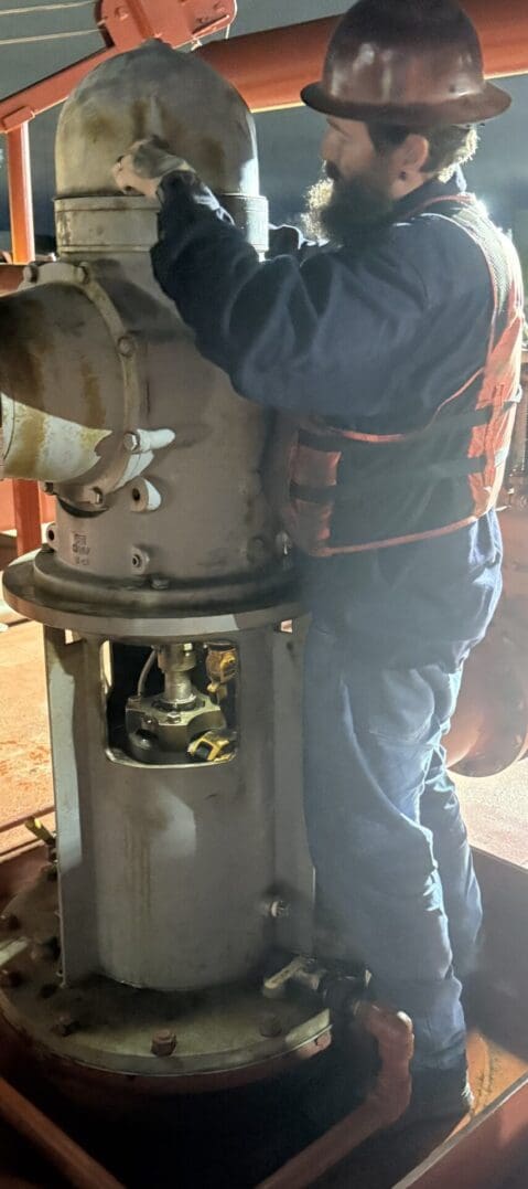 Worker inspecting industrial machinery at night.